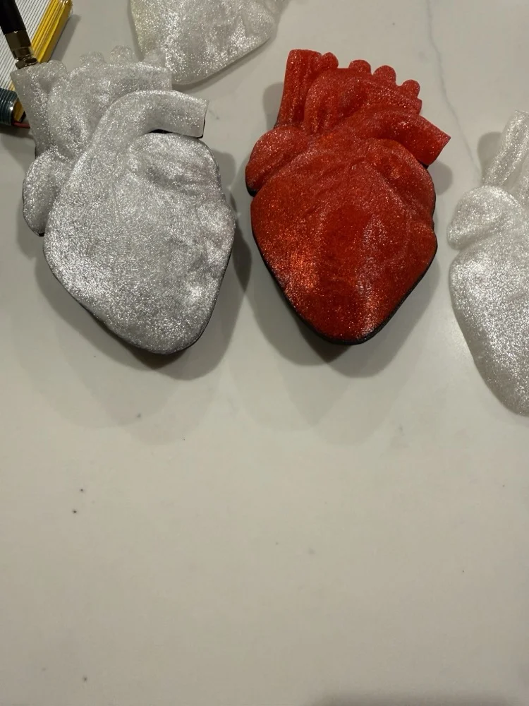 3D-printed heart shells for the Heart Badge in silver and red glitter finishes